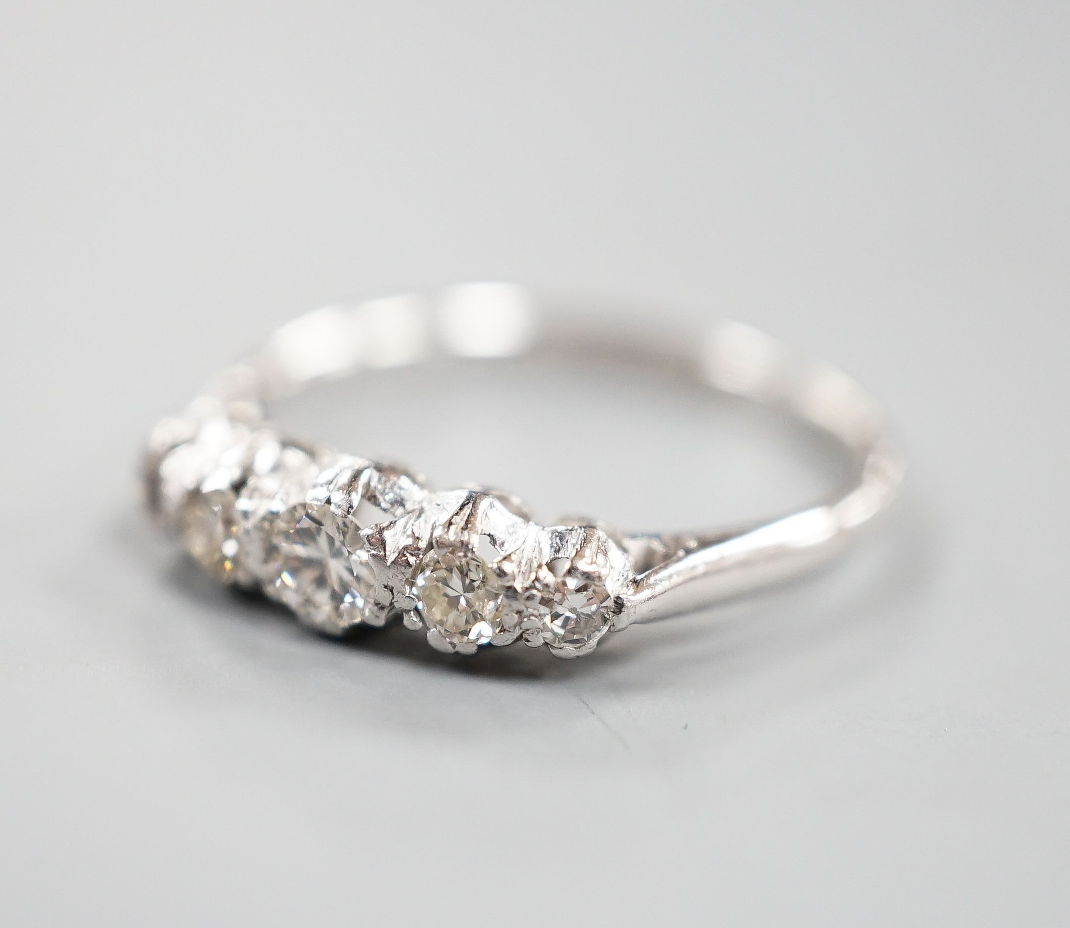 An 18ct & plat, graduated five stone diamond half hoop ring, size L/M, gross weight 2 grams.